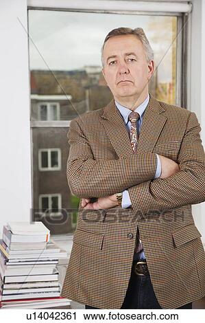 Stock Image - Portrait of confident businessman with arms crossed in office. Fotosearch
