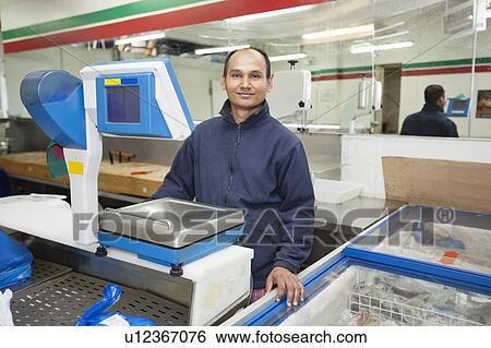 Portrait of confident male employee standing in front on weighing machine at grocery store View Large Photo Image Stock Photograph - Portrait of confident male employee standing in front on weighing machine at grocery store. Fotosearch
