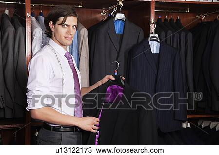 Portrait of confident man holding new suit in store View Large Photo Image Stock Image - Portrait of confident man holding new suit in store. Fotosearch