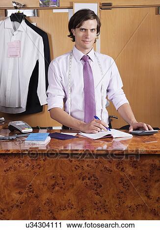 Portrait of confident owner making bills at counter View Large Photo Image Stock Image - Portrait of confident owner making bills at counter. Fotosearch