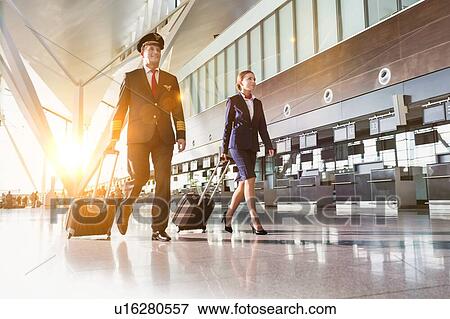 Portrait of confident pilot with stewardess walking in airport View Large Photo Image Stock Photo - Portrait of confident pilot with stewardess walking in airport. Fotosearch