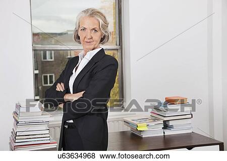 Portrait of confident senior businesswoman with arms crossed in office View Large Photo Image Stock Photo - Portrait of confident senior businesswoman with arms crossed in office. Fotosearch