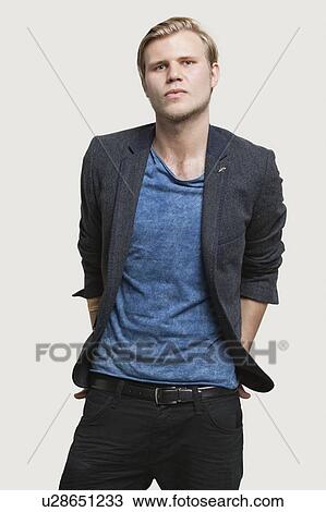 Stock Image - Portrait of confident young businessman in smart casuals against gray background. Fotosearch