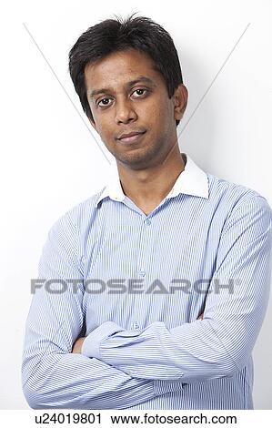Portrait of confident young Indian man with arms crossed standing against white background View Large Photo Image Stock Image - Portrait of confident young Indian man with arms crossed standing against white background. Fotosearch