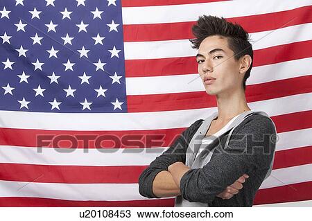 Portrait of confident young man with arms crossed standing against American flag View Large Photo Image Stock Image - Portrait of confident young man with arms crossed standing against American flag. Fotosearch