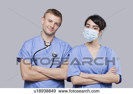 Stock Photo - Portrait of female and male surgeons standing with arms crossed over gray background. Fotosearch