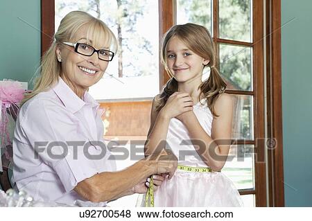 Stock Photo - Portrait of grandmother measuring granddaughter's waist with tape. Fotosearch