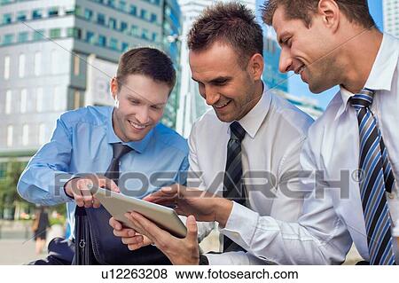 Portrait of handsome businessman showing business plan to the other businessman over digital tablet while sitting View Large Photo Image Stock Photo - Portrait of handsome businessman showing business plan to the other businessman over digital tablet while sitting. Fotosearch