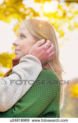 Portrait of handsome man showing affection to his wife in park with lens flare  View Large Photo Image Stock Photo - Portrait of handsome man showing affection to his wife in park with lens flare . Fotosearch