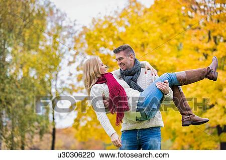 Portrait of handsome mature man carrying his wife while walking in park View Large Photo Image Stock Image - Portrait of handsome mature man carrying his wife while walking in park. Fotosearch