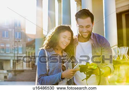 Portrait of handsome young man showing pictures on camera to his beautiful girlfriend while standing against museum with lens flare in background View Large Photo Image Stock Image - Portrait of handsome young man showing pictures on camera to his beautiful girlfriend while standing against museum with lens flare in background. Fotosearch
