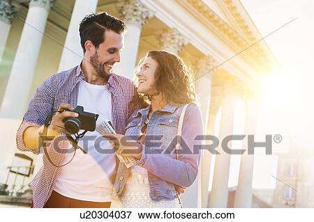 Portrait of handsome young man showing pictures on camera to his beautiful girlfriend while sitting against museum with lens flare in background View Large Photo Image Stock Photo - Portrait of handsome young man showing pictures on camera to his beautiful girlfriend while sitting against museum with lens flare in background. Fotosearch