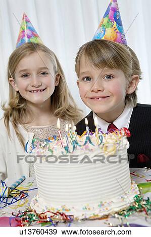 Stock Photo - Portrait of happy birthday boy with sister and cake. Fotosearch