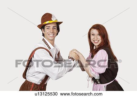 Stock Image - Portrait of happy couple dancing against gray background. Fotosearch