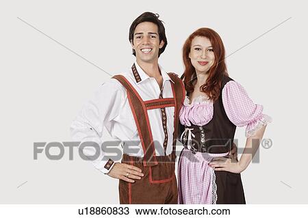 Stock Image - Portrait of happy couple in costume standing against gray background. Fotosearch