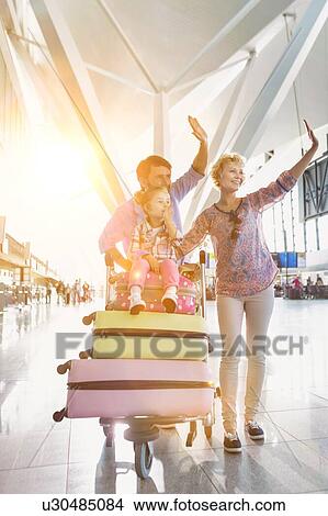 Portrait of happy family waving in arrival area at airport View Large Photo Image Picture - Portrait of happy family waving in arrival area at airport. Fotosearch