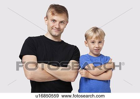 Stock Photo - Portrait of happy father and son in casuals with arms crossed over white background. Fotosearch