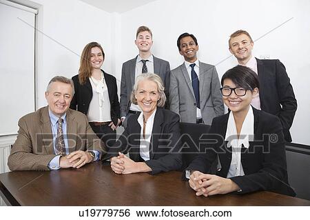 Stock Photograph - Portrait of happy multiethnic business group at desk in office. Fotosearch