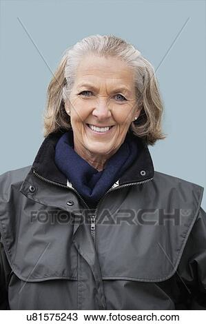 Stock Image - Portrait of happy senior woman against blue background. Fotosearch
