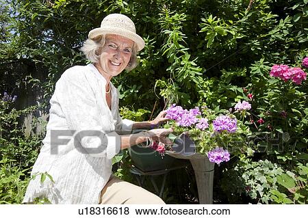 Stock Photo - Portrait of happy senior woman with shovel gardening in backyard. Fotosearch