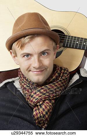 Stock Photography - Portrait of happy young Caucasian man with guitar over white background. Fotosearch