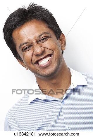 Stock Image - Portrait of happy young Indian man against white background. Fotosearch