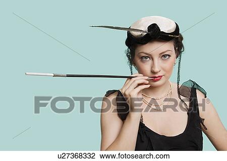 Portrait of happy young woman holding old-fashioned cigarette holder against blue background View Large Photo Image Stock Image - Portrait of happy young woman holding old-fashioned cigarette holder against blue background. Fotosearch