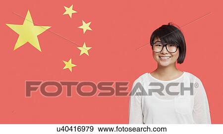 Stock Photo - Portrait of happy young woman wearing eyeglasses against Chinese flag. Fotosearch