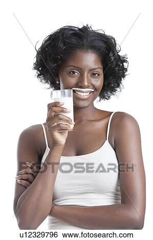 Stock Photograph - Portrait of happy young woman with milk moustache holding glass of milk. Fotosearch