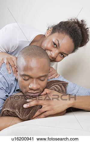 Stock Image - Portrait of happy young woman with partner sleeping on sofa. Fotosearch