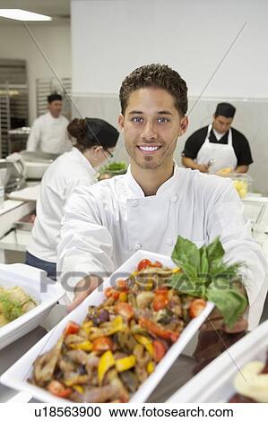 Portrait of male chef holding salad with coworkers in background View Large Photo Image Stock Image - Portrait of male chef holding salad with coworkers in background. Fotosearch