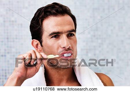 Portrait of man brushing his teeth while looking in to the mirror View Large Photo Image Stock Photo - Portrait of man brushing his teeth while looking in to the mirror. Fotosearch