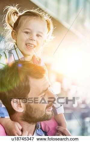Portrait of man carrying his daughter on his shoulder in airport with lens flare View Large Photo Image Stock Photo - Portrait of man carrying his daughter on his shoulder in airport with lens flare. Fotosearch