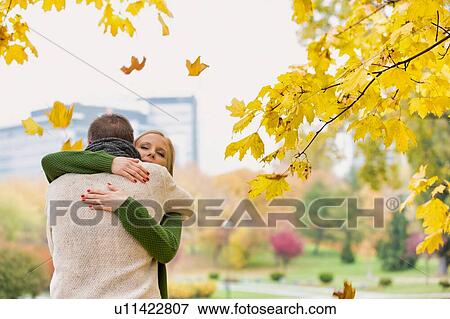 Portrait of man embracing his beautiful wife in park View Large Photo Image Stock Photo - Portrait of man embracing his beautiful wife in park. Fotosearch