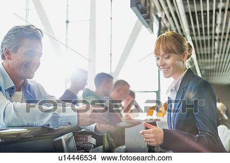 Picture - Portrait of man giving his passport for check in with passenger service agent at airport . Fotosearch