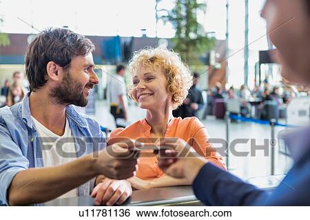 Portrait of man giving passport to passenger service agent to get his boarding pass in airport View Large Photo Image Stock Photograph - Portrait of man giving passport to passenger service agent to get his boarding pass in airport. Fotosearch