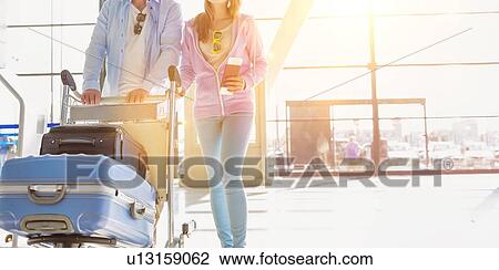 Portrait of man pushing baggage cart for check in with her daughter at airport View Large Photo Image Stock Image - Portrait of man pushing baggage cart for check in with her daughter at airport. Fotosearch