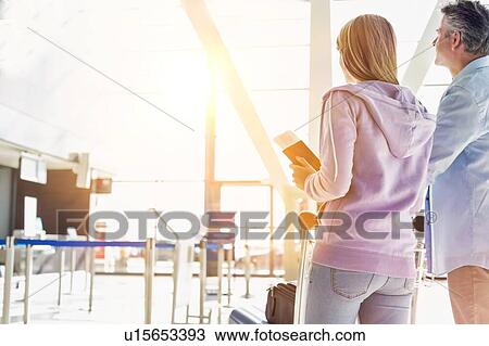 Stock Image - Portrait of man pushing baggage cart for check in with her daughter at airport. Fotosearch