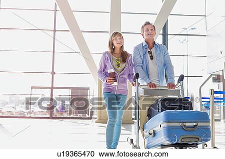 Portrait of man pushing baggage cart for check in with her daughter at airport View Large Photo Image Stock Image - Portrait of man pushing baggage cart for check in with her daughter at airport. Fotosearch