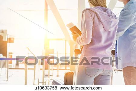 Stock Photo - Portrait of man pushing baggage cart for check in with her daughter at airport. Fotosearch
