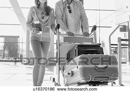 Portrait of man pushing baggage cart for check in with her daughter at airport View Large Photo Image Stock Photograph - Portrait of man pushing baggage cart for check in with her daughter at airport. Fotosearch