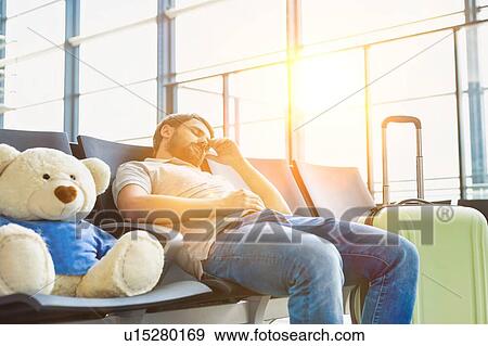 Stock Photo - Portrait of man sleeping and lying on chair while waiting for his flight in airport. Fotosearch