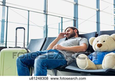 Portrait of man sleeping and lying on chair while waiting for his flight in airport View Large Photo Image Stock Photo - Portrait of man sleeping and lying on chair while waiting for his flight in airport. Fotosearch