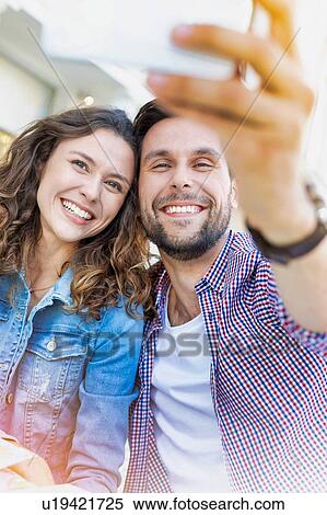 Stock Photography - Portrait of man taking selfie with his beautiful girlfriend. Fotosearch