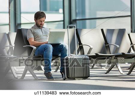 Stock Image - Portrait of man working with his laptop while waiting for boarding in airport. Fotosearch