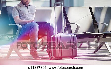 Portrait of man working with his laptop while waiting for boarding in airport View Large Photo Image Stock Image - Portrait of man working with his laptop while waiting for boarding in airport. Fotosearch