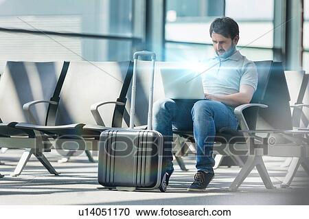 Stock Image - Portrait of man working with his laptop while waiting for boarding in airport. Fotosearch