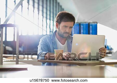 Portrait of man working with his laptop in cafe at airport while waiting for his flight View Large Photo Image Stock Image - Portrait of man working with his laptop in cafe at airport while waiting for his flight. Fotosearch