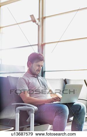 Portrait of man working with his laptop while waiting for boarding in airport View Large Photo Image Stock Photo - Portrait of man working with his laptop while waiting for boarding in airport. Fotosearch