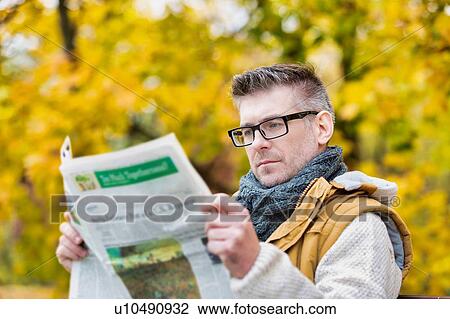 Portrait of mature attractive man sitting on bench while reading newspaper in park View Large Photo Image Stock Image - Portrait of mature attractive man sitting on bench while reading newspaper in park. Fotosearch